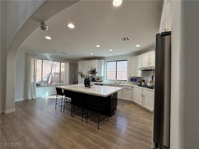 kitchen featuring gas stovetop, white cabinetry, a kitchen island, and light hardwood / wood-style floors