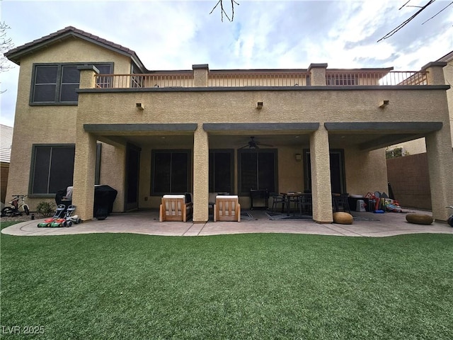 rear view of property featuring a yard, a patio area, a balcony, and ceiling fan