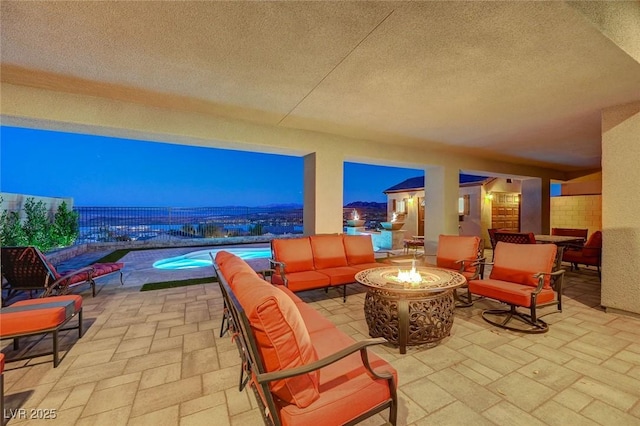 patio terrace at dusk featuring a fenced in pool and an outdoor living space with a fire pit