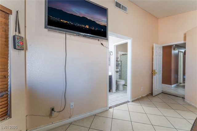 unfurnished bedroom with ensuite bathroom and light tile patterned flooring