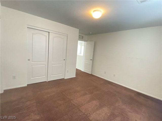 unfurnished bedroom featuring dark carpet and a closet