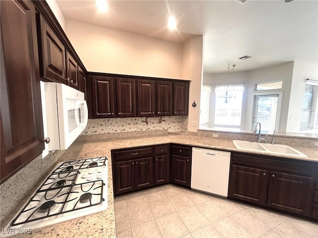 kitchen featuring white appliances, dark brown cabinetry, sink, and light tile patterned floors