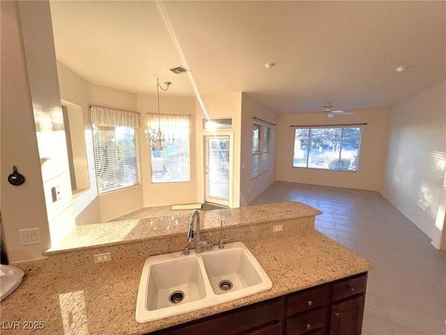 kitchen featuring light stone countertops, sink, a wealth of natural light, and dark brown cabinets