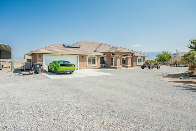 view of front of house featuring central AC, a garage, and solar panels