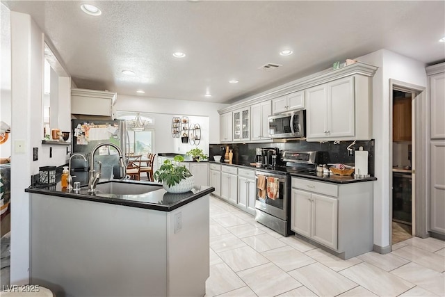 kitchen with appliances with stainless steel finishes, sink, white cabinets, backsplash, and kitchen peninsula