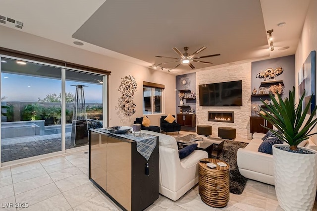 tiled living room featuring rail lighting, a large fireplace, and ceiling fan