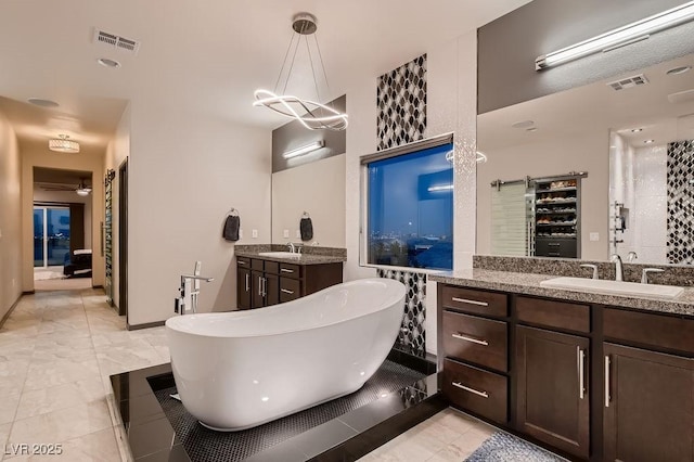 bathroom featuring an inviting chandelier, vanity, and a bath