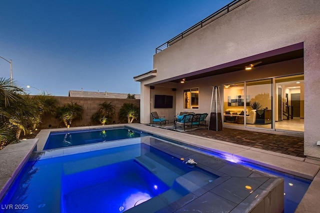 pool at dusk featuring an in ground hot tub and an outdoor living space