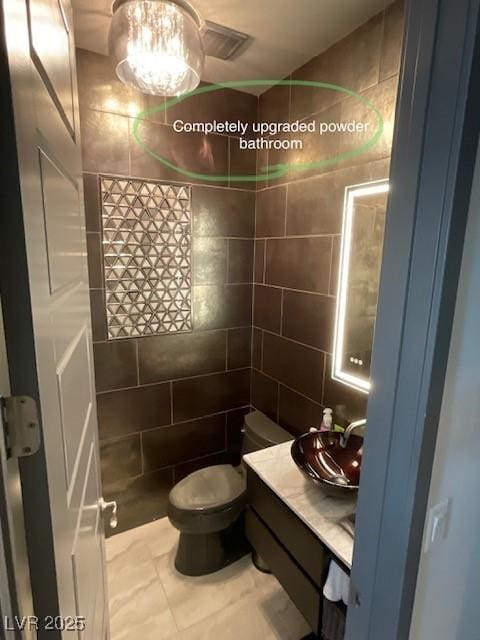 bathroom featuring tile walls, vanity, and toilet