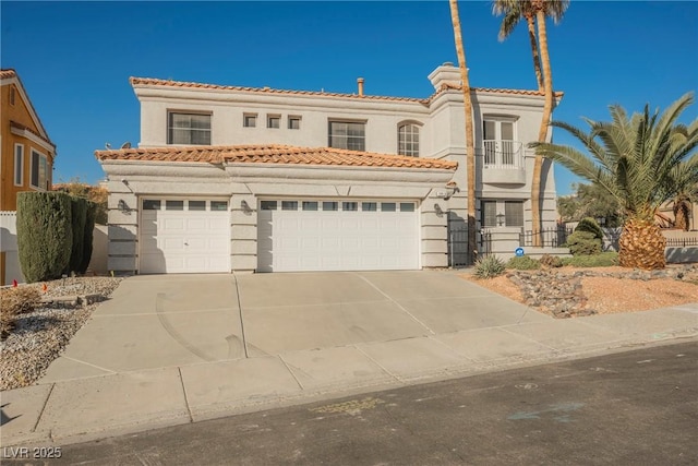 mediterranean / spanish home with driveway, a tile roof, a garage, and stucco siding