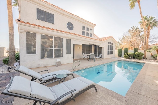 back of property featuring a tile roof, fence, a fenced in pool, and a patio