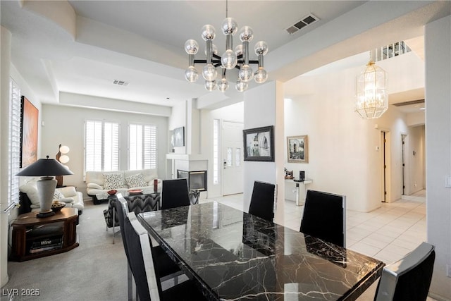 dining space with light tile patterned flooring, a tray ceiling, and a chandelier