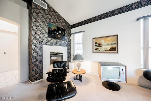 sitting room with lofted ceiling, light tile patterned floors, and a high end fireplace