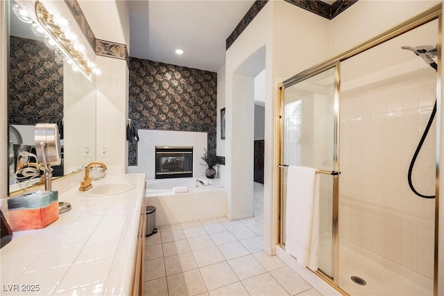 bathroom with a tile fireplace, plus walk in shower, tile patterned floors, and vanity