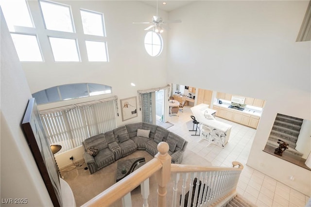 living room featuring ceiling fan, light tile patterned floors, and a high ceiling