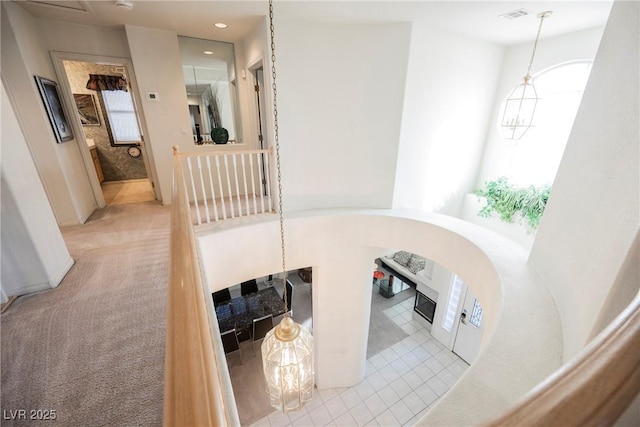 hall with a notable chandelier and light colored carpet