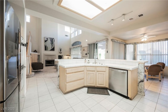 kitchen with sink, light tile patterned floors, tile counters, and appliances with stainless steel finishes