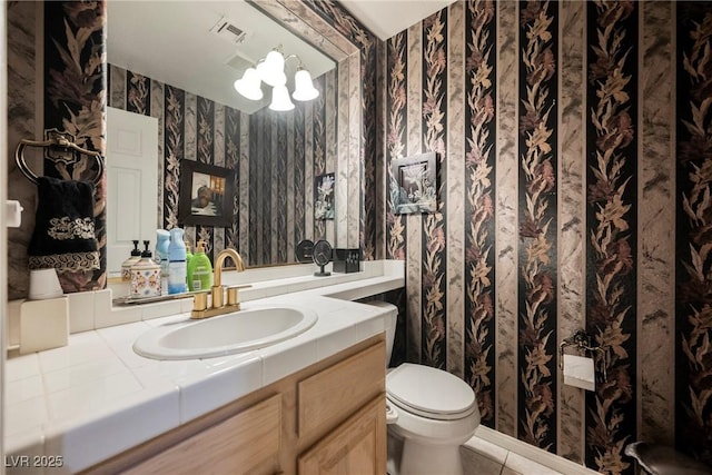 bathroom featuring tile patterned flooring, vanity, a chandelier, and toilet