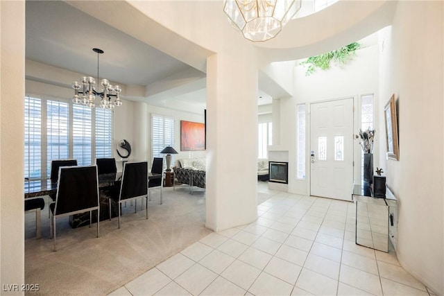 entrance foyer featuring a high ceiling, light colored carpet, and a chandelier