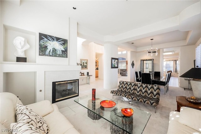 living room featuring an inviting chandelier, a fireplace, and a raised ceiling