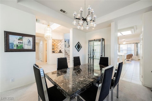 dining space featuring light colored carpet, a notable chandelier, and a tray ceiling