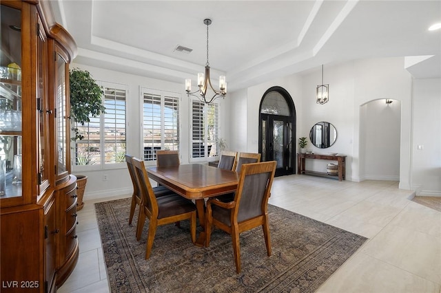 tiled dining space featuring a raised ceiling and a notable chandelier