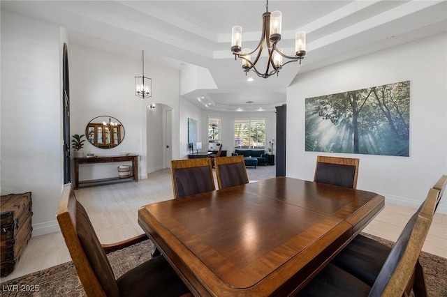 dining area with an inviting chandelier, a towering ceiling, and a tray ceiling