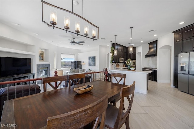 dining area with light tile patterned floors, sink, a premium fireplace, and ceiling fan