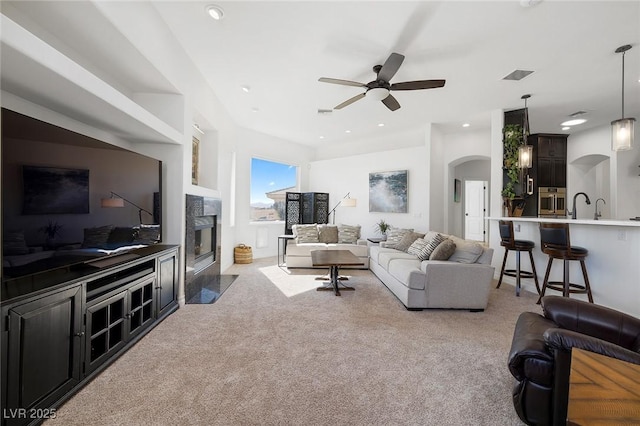 carpeted living room featuring ceiling fan, sink, and a fireplace