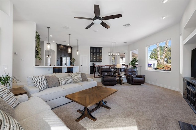 living room featuring ceiling fan with notable chandelier and light carpet