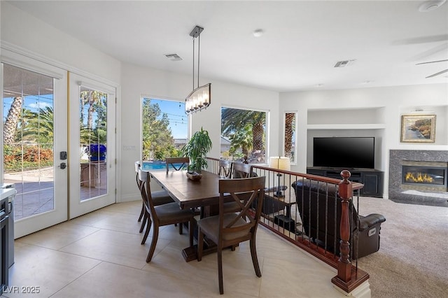 dining area with french doors, plenty of natural light, a notable chandelier, and built in shelves