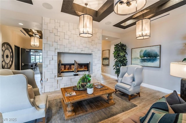 living room with a chandelier, a fireplace, and light wood-type flooring