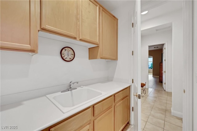 kitchen with light brown cabinetry, sink, and light tile patterned floors