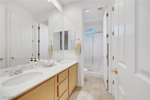 bathroom featuring tile patterned floors, toilet, a shower with shower door, and vanity