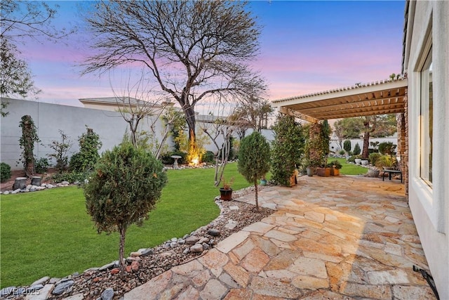 patio terrace at dusk featuring a pergola and a lawn