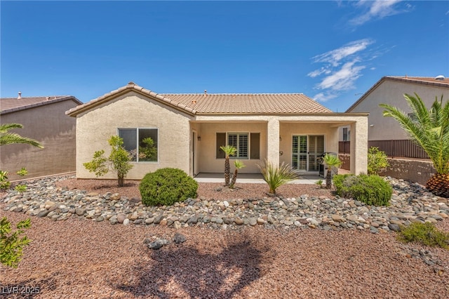 back of property featuring fence, stucco siding, and a tile roof