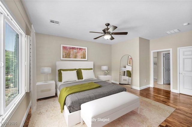 bedroom featuring wood finished floors, visible vents, a ceiling fan, and baseboards