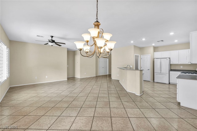kitchen featuring freestanding refrigerator, light tile patterned floors, white cabinets, ceiling fan with notable chandelier, and visible vents