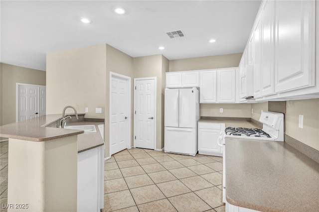 kitchen with a peninsula, white cabinets, freestanding refrigerator, and a sink
