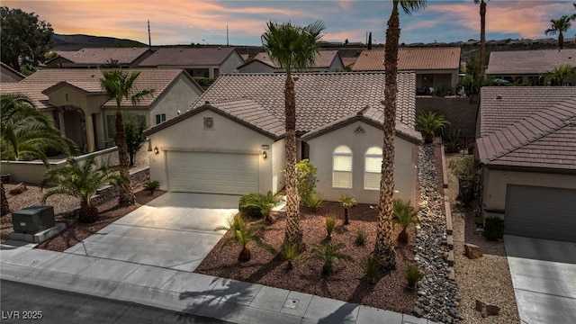 mediterranean / spanish-style home with a tiled roof, stucco siding, concrete driveway, and an attached garage