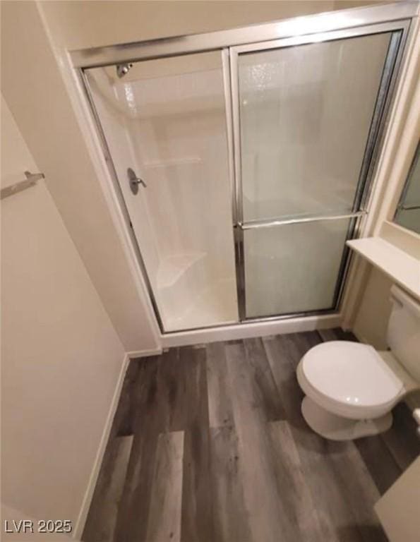 bathroom featuring wood-type flooring, an enclosed shower, and toilet