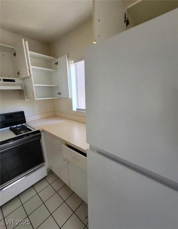 kitchen featuring white cabinetry, light tile patterned floors, and white appliances