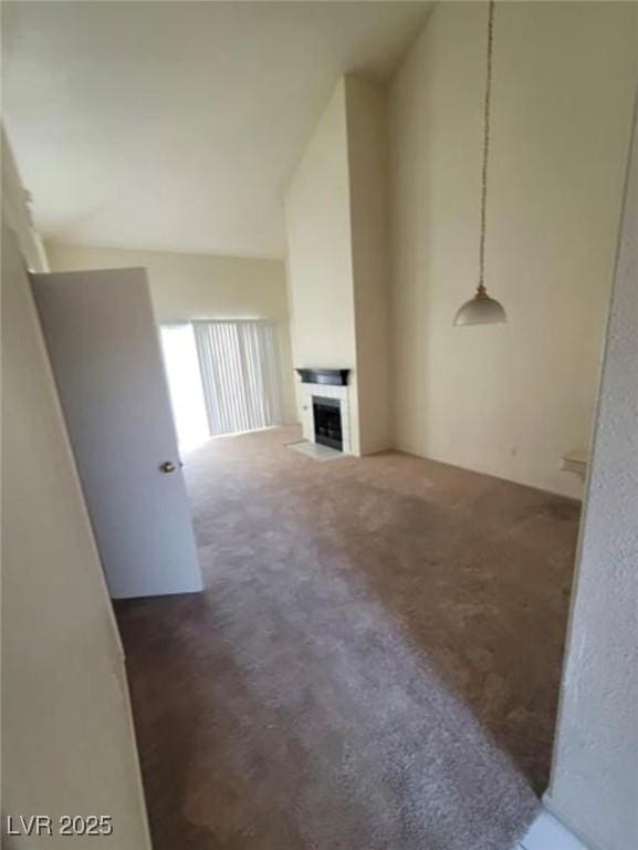 unfurnished living room featuring high vaulted ceiling and dark colored carpet