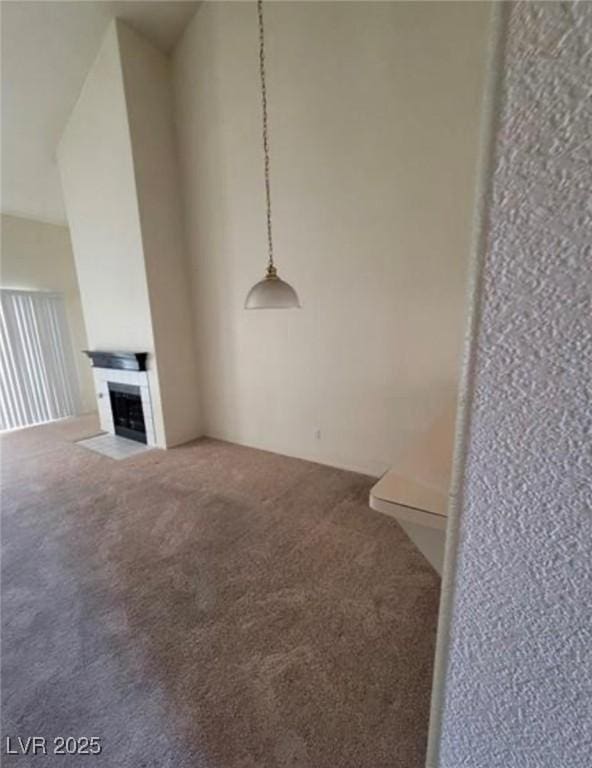 unfurnished living room with a towering ceiling, carpet floors, and a tile fireplace