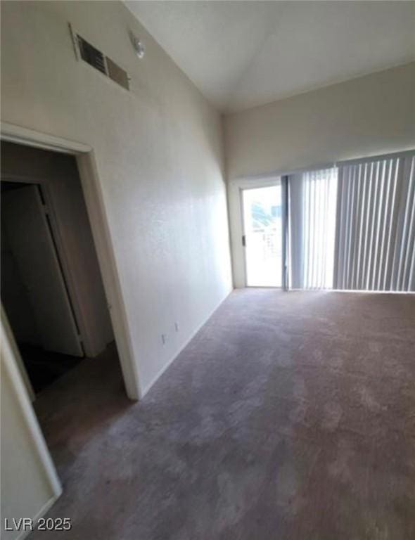 carpeted empty room with high vaulted ceiling