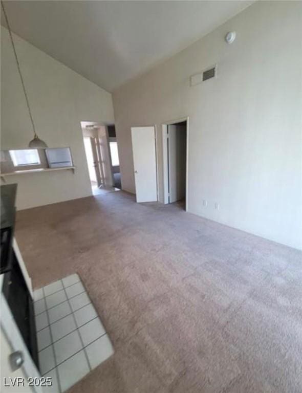 unfurnished living room featuring carpet and high vaulted ceiling