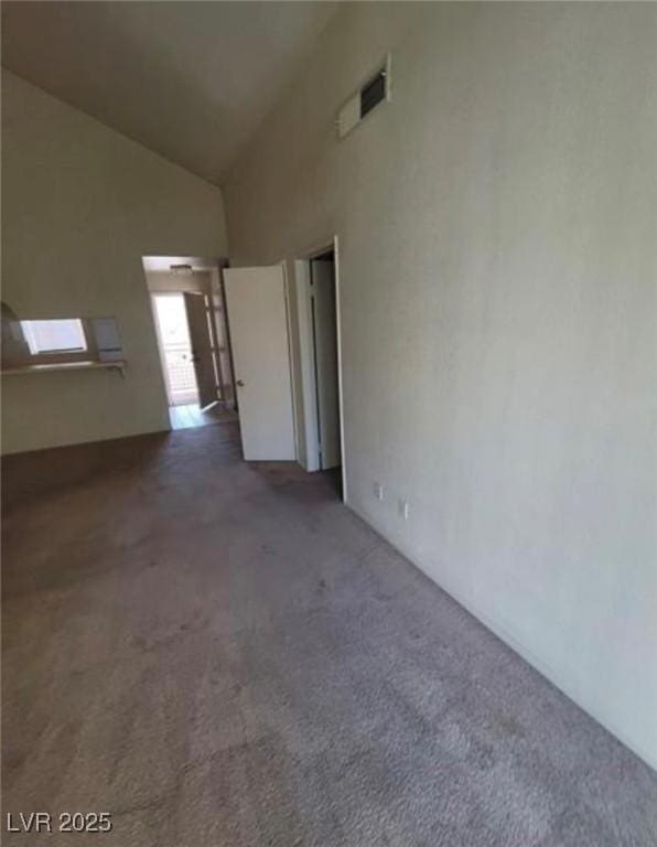 spare room with high vaulted ceiling and dark colored carpet