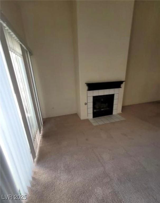 unfurnished living room with a tile fireplace and light colored carpet