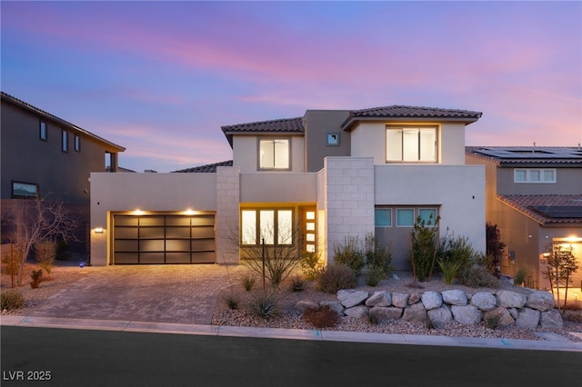 view of front of home with a garage, a tiled roof, decorative driveway, and stucco siding