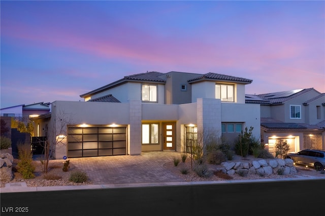 view of front of home featuring a garage, a tile roof, decorative driveway, and stucco siding